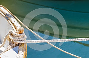 Nautical rope tied on wooden boat deck cleat at shore