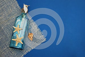 Nautical Theme Backdrop, Decorative Bottle with Shells, Starfish on Depp blue Background.Copy Space. Selective focus. photo