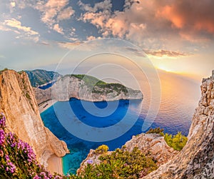 Navagio beach with shipwreck and flowers against sunset on Zakynthos island in Greece