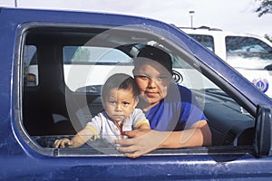 Navajo teenage girl and baby looking out of car window, Kayenta, AZ