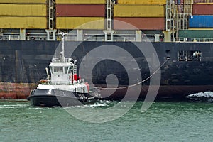 Naval tug moving a container ship