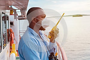 Navigation officer with protective mask, speaks by radio. Collision prevention at sea