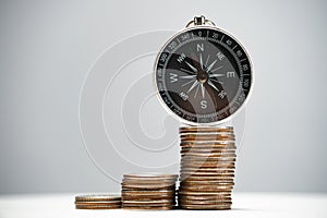 Navigational compass on a stack of coins with growth. Concept of investment strategy and success.