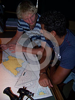 Navigational duty officer explaining to cadet how to insert the position into the sea chart