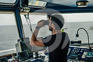 Navigational officer lookout on navigation watch looking through binoculars