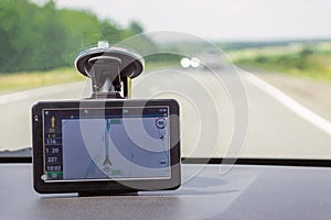 The navigator is located on the front window of the car indicating the way to the driver during the journey