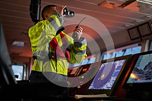 Navigator. pilot, captain as part of ship crew performing daily duties with VHF radio, binoculars on board of modern ship with photo