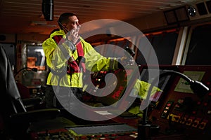 Navigator. pilot, captain as part of ship crew performing daily duties with VHF radio, binoculars on board of modern ship with