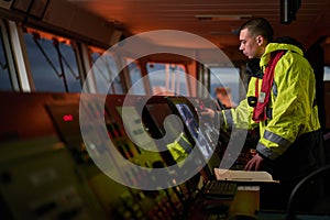 Navigator. pilot, captain as part of ship crew performing daily duties with VHF radio, binoculars on board of modern ship with