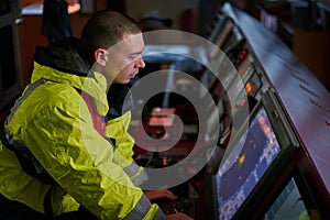 Navigator. pilot, captain as part of ship crew performing daily duties with VHF radio, binoculars on board of modern ship with