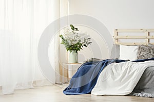 Navy blue blanket thrown on double bed with lights on bedhead st photo