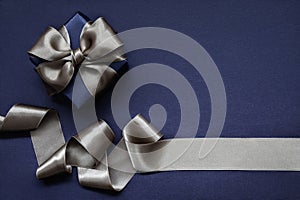 Navy blue gift box tied with beige ribbon on a navy blue background