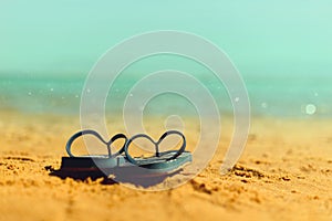 Navy flip flop on yellow sand beach with blue sea and sky background. Copy space. Summer, holiday and travel concept