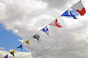 Navy ship signal flags against clouds.