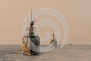 Navy warship fleet underway in formation in the sea when sundown