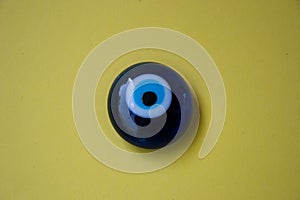 Glass Turkish eye `Nazar Boncugu` on pale background, object, superstition concept, indoors photo