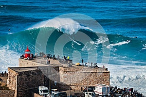 Nazare, Portugal, Surfer Riding Giant Wave in Front of Nazare Lighthouse photo