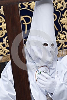 Nazarene wearing a capirote and carrying a cross