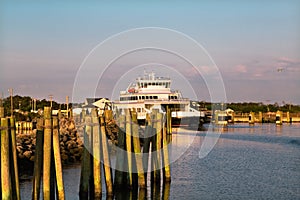 NC USA. Sun rise Pink clouds sky, reflections in water.Ferry at the pier