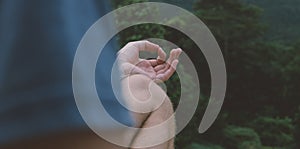 NClose-up male hands of a meditating guy on a green background. Mudras for Yoga