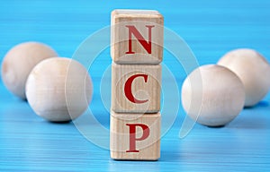 NCP - acronym on wooden cubes on a blue background with wooden round balls photo