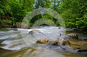 ND filter photo. Milk water flow rapid stream. Caucasus rocky mountain river in forest.