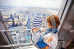 Nd her toddler son looking out of the window, while visiting At The Top - Observation Deck