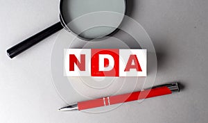 NDA word on wooden cubes with pen and magnifier