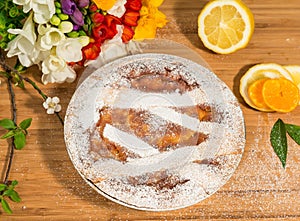 Neapolitan easter pie sprinkled with icing sugar and decorated with freesia and fresh fruits.