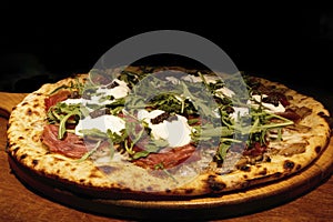 Neapolitan pizza (Naples pizza) with buffalo mozzarella cheese, parma ham decorated with fresh arugula.