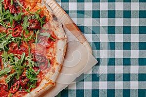 Neapolitan spicy pizza with ham, cheese, arugula, basil, tomatoes, pepperoni pepper sprayed with cheese on a wooden board on a