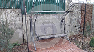 Near the concrete fence in the garden are wide metal swings for comfortable relaxation. They can be covered with an awning to prot