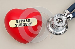 Near the stethoscope lies a heart on which a sticker is pasted with the inscription - Bypass Surgery