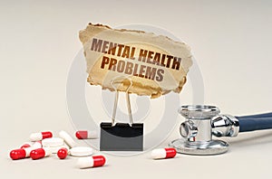 Near the stethoscope are pills and a clip with a cardboard sign - mental health problems