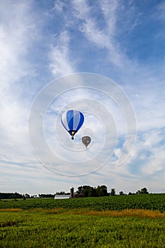 Near Wausau, Wisconsin, USA, July 10, 2021, Taste N Glow Balloon Fest. Two hot air balloons in the the sky looking for a place to
