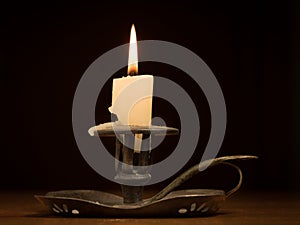Nearly burnt down burning candle on old candle holder