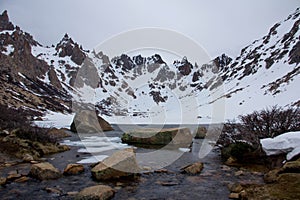A nearly frozen lake amidst mountains photo