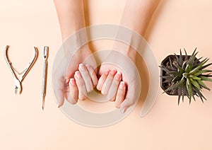 Neat beautiful french manicure on the hands of a young woman. Tool for cutting nails. Minimalism concept for nail care