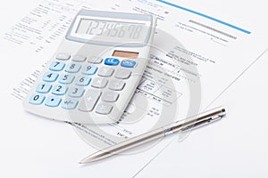 Neat calculator with silver pen and utility bill under it photo