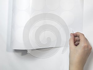A neat female hand peels off the round white sticker