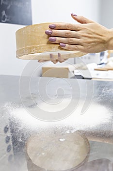 Neat female hands with manicure sift flour through a sieve