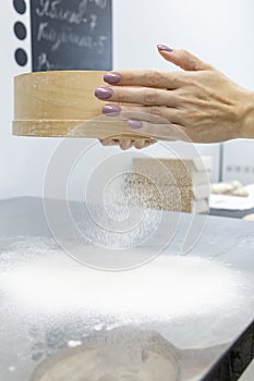 Neat female hands with manicure sift flour through a sieve