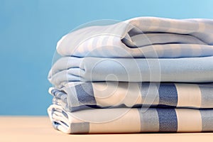 neat stack of white and blue shirts, along with other garments, hanging on table. Image exudes sense of order and style, as shirts