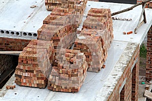 Neat stacks of red bricks lit by summer sun piled on basement fl