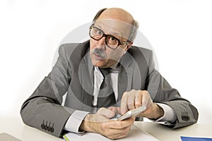 Neat and tidy 60s mature senior business man using mobile phone at office desk working happy and gesturing funny