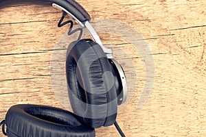 Neat vintage headphones on wooden table - retro music concept. Filtered image: cross processed vintage effect.