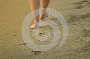 Neat womans feet making a trace in the sandy beach - holiday memories.