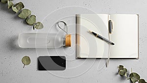 A neatly arranged flat lay features an open notebook with blank pages and a