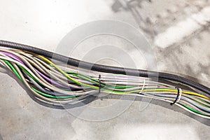 Neatly bundled multicolored electrical wires encased in flexible conduit on a concrete surface