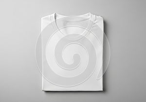 A neatly folded white T-shirt is placed against a smooth, light gray